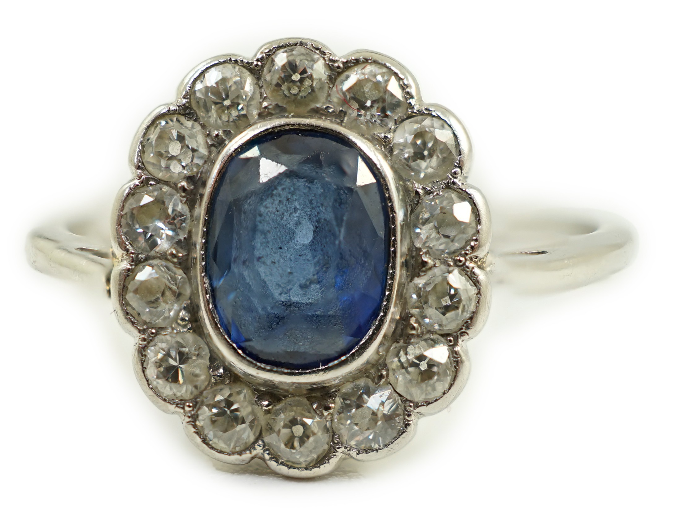 A white metal, sapphire and diamond set oval cluster ring, size M/N, gross weight 2 grams.